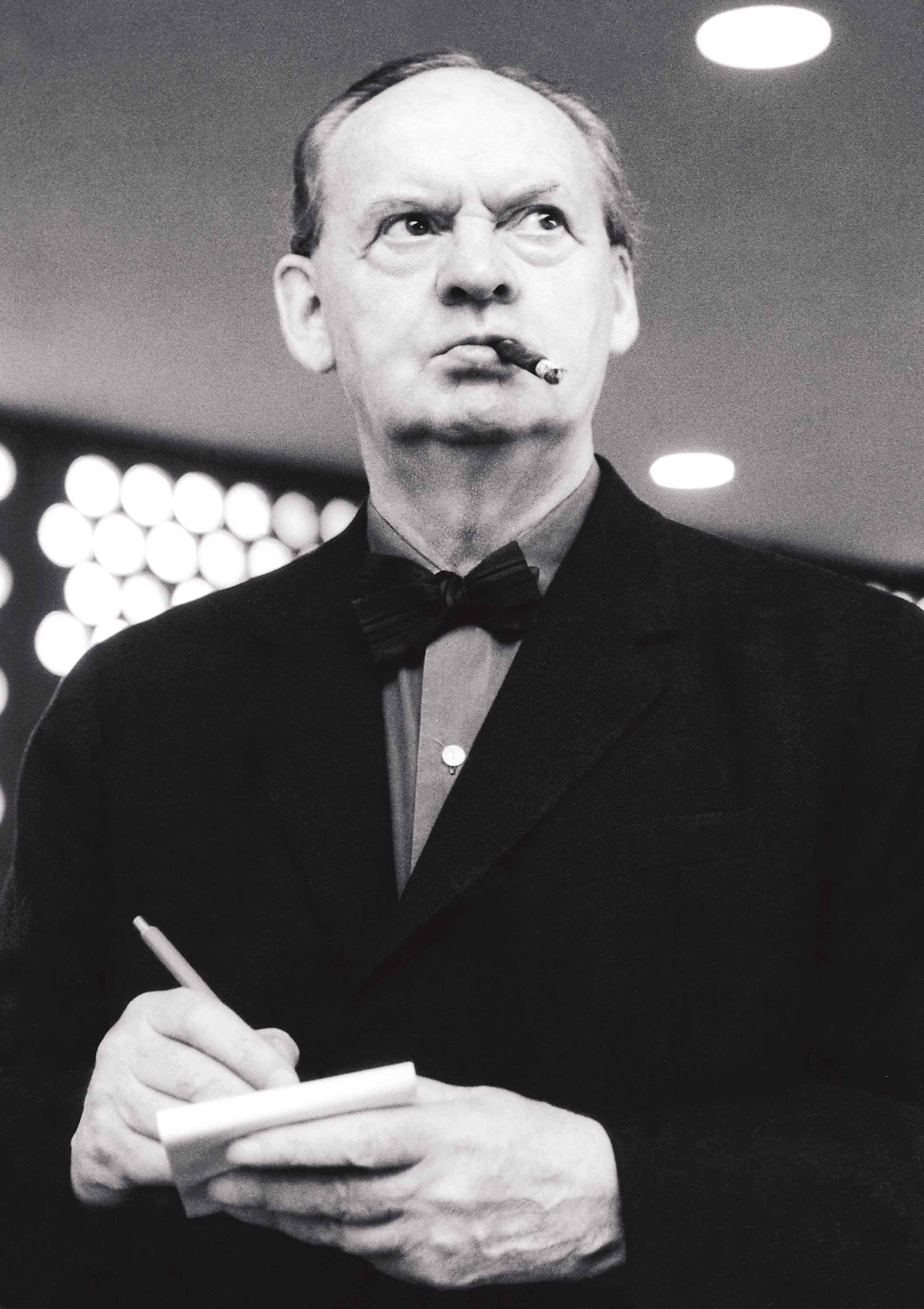 Hans Scharoun with a cigarette in his mouth and a note pad and pencil in his hands.